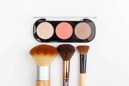 Makeup brushes of different sizes and makeup powder on a white background. Top view.の写真素材