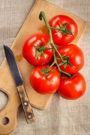 Juicy red tomatoes on a cutting board with a knife. Top view.の写真素材