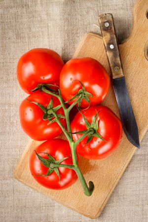 Juicy red tomatoes on a cutting board with a knife. Top view.の写真素材
