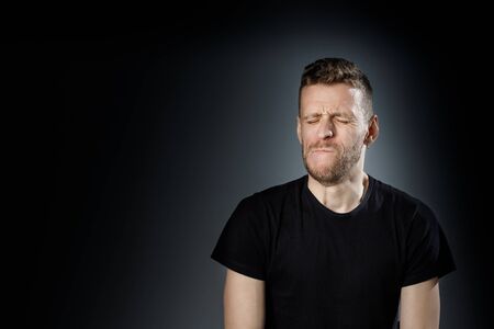 Young man, showing painfull, toothache emotions on black background.の写真素材