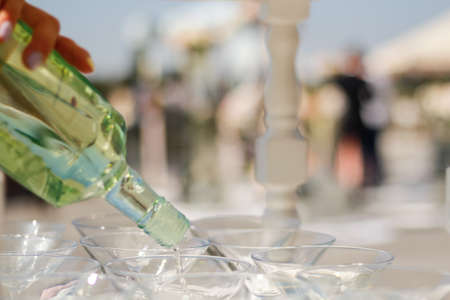 Woman pours wine from a bottle into glassesの写真素材