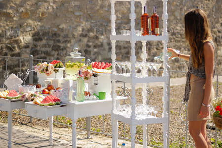 The girl pours wine by the glass at the buffet table at the weddingの写真素材