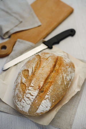 Freshly baked tartin bread and a knife on a wooden board.の写真素材