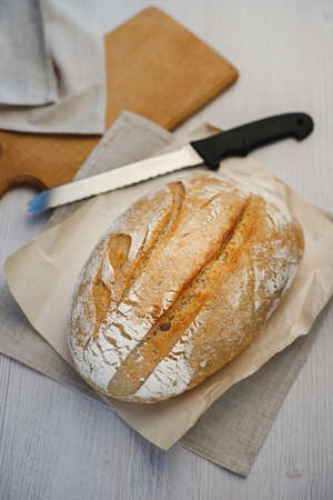Freshly baked tartin bread and a knife on a wooden board