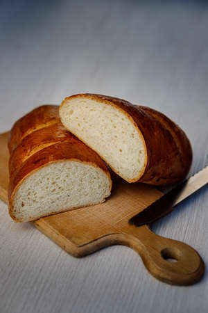 Delicious freshly baked bread and a knife on the kitchen boardの写真素材