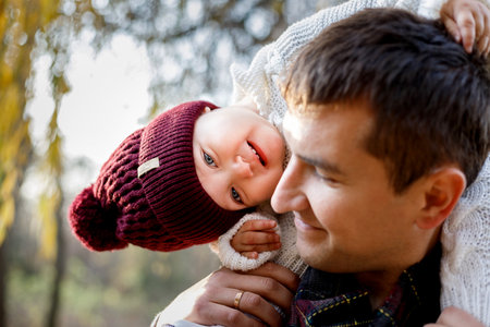 A father holds his smiling daughter on his shoulders.