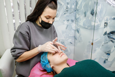 Kamyanets-Podilskyi, Ukraine - February 03, 2021: Cosmetologist massages the face of a young girl after the peeling procedure.のeditorial素材