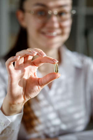 The girl holds a fish oil capsule in her hand. Omega-3 capsules in the doctor's hand.の写真素材