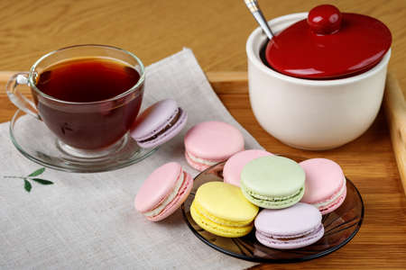 Multicolored macaroons and a cup of tea on a wooden tray. Morning tea and sweets.の写真素材