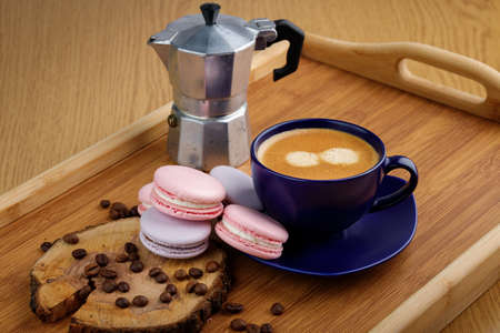 Cup of coffee, macaroons, and coffee beans on a platter and geyser coffee maker on a wooden trayの写真素材