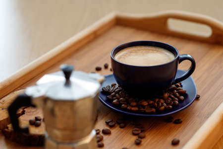 Cup of coffee and coffee beans on a platter and geyser coffee maker on a wooden trayの写真素材