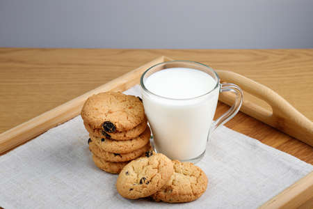 Cup of milk and cookies with raisins on a wooden trayの写真素材