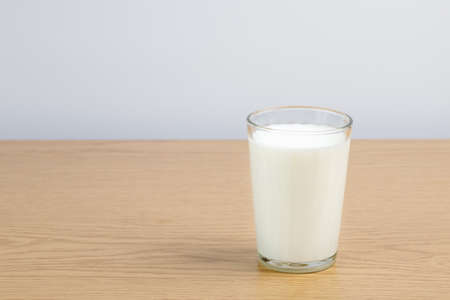 A glass of milk on a wooden table on a white backgroundの写真素材