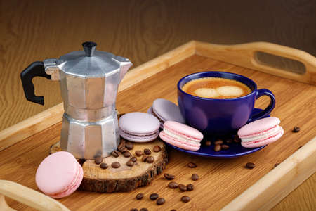 Cup of coffee, macaroons, and coffee beans on a platter and geyser coffee maker on a wooden trayの写真素材