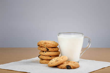 Cup of milk and cookies with raisins on a wooden tableの写真素材