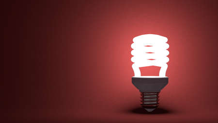 Glowing spiral light bulb on dark red textured background
