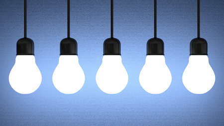 Row of hanging glowing tungsten light bulbs on blue textured backgroundの写真素材
