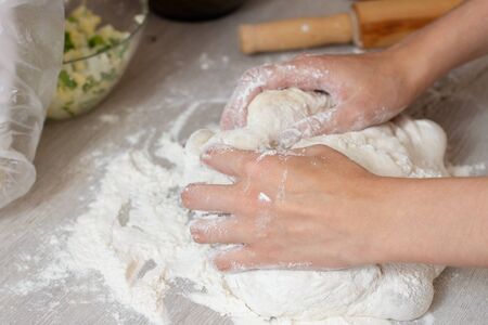 female hands making dough on a table