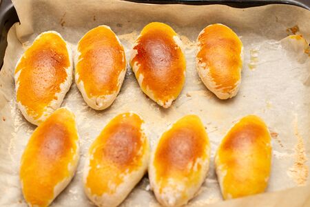 oven-baked pastry pies on baking paper, close up
