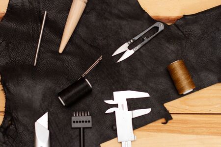 Set of leather work tools on black leather and wooden boardsの写真素材