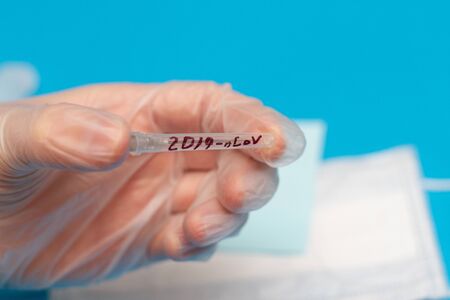 doctor's hand in a surgical glove with a test tube with the inscription