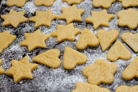 a cookies made from dough in the shape of hearts and stars on a baking sheet with flourの写真素材