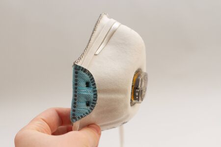 PPE mask respirator holds in hand on a white background