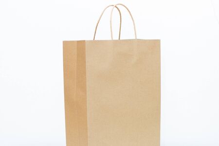 Brown paper craft bag isolated on white background. Recycled paper shopping bag, informed consumptionの写真素材