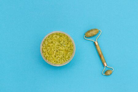 green sea salt in a jar and stone roller massager on a blue backgroundの写真素材