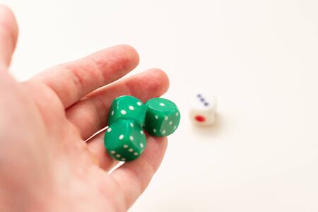Male hand rolling green dice on white background