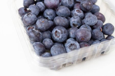 ripe blueberry in a transparent plastic container on a white backgroundの写真素材