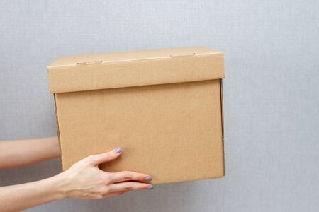 a Woman holds out her hands with a cardboard box. The courier delivered the parcel.の写真素材