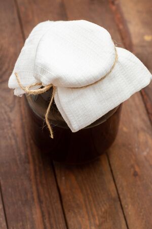 brown glass jar with harvesting on wooden background.の写真素材