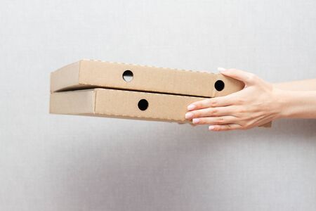two packs of pizza in female hands on a gray backgroundの写真素材