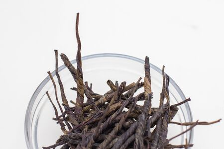 Dried kudin green tea leaves in glass bowl on white background.の写真素材