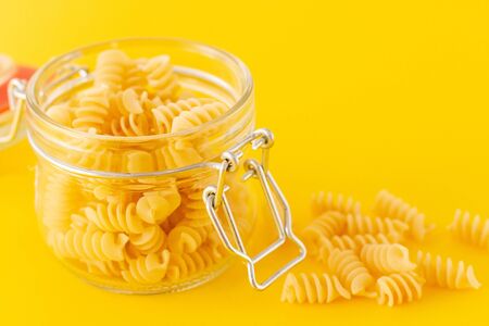 fusilli pasta in galss jar on yellow background.の写真素材