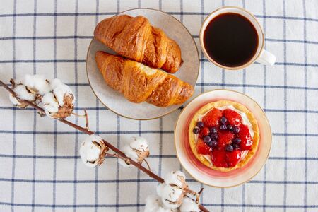 Strawberry cake and croissants with a cup of coffee on the table. Nice breakfast.の写真素材