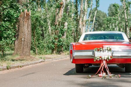 A retro car decorated for a wedding with the words just married and tin cans on ribbons. Wedding decorations outdoor. Beautiful wedding car with plate Just Married.の写真素材