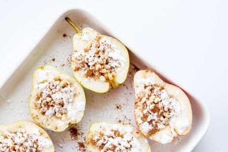 Halves of pears with nuts, cinnamon and icing sugar on a white background. Dessert recipe.の写真素材