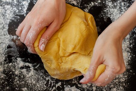 Female hands making dough. Process prepare and kneading dough on black background. Food concept.の写真素材