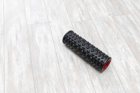 Black bumpy foam roller for yoga and massage on floorの写真素材