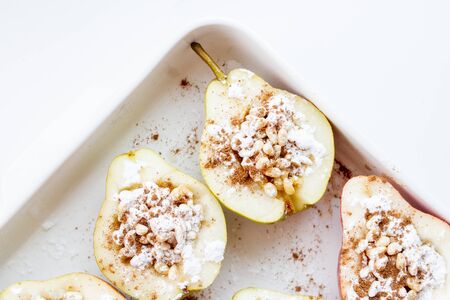 Stuffed pears dessert in white baking dish. Halves of pears with nuts, cinnamon and icing sugar. Dessert recipe.の写真素材