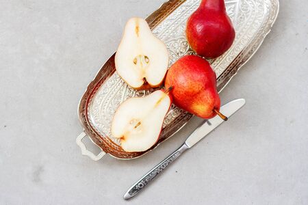 Ripe pear in the tray with a knife on gray concrete surface background.の写真素材