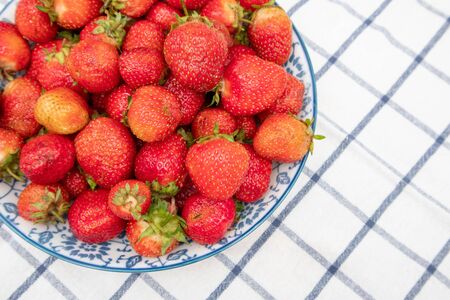 Fresh organic strawberries in bowl on on a checkered napkin.の写真素材