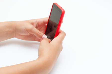 Child hands holding a smartphone with red cover case. Free space.の写真素材