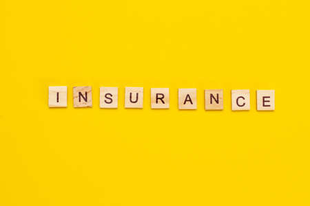 INSURANCE inscription from wooden cubes on yellow background.の写真素材
