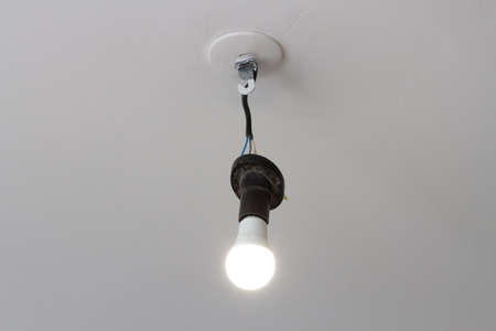 Light bulb in a cartridge with wires from the ceiling on a white background. Selective focusの写真素材