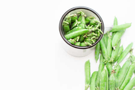 Green peas in a white metal mug and on a plate. Selective focus. Free space for text.の写真素材