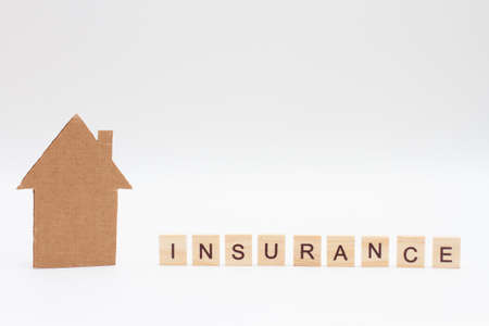 A model of house and word INSURANCE made of wooden blocks on white background. Homeowners Insurance.の写真素材