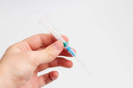 Hand holding syringe on white